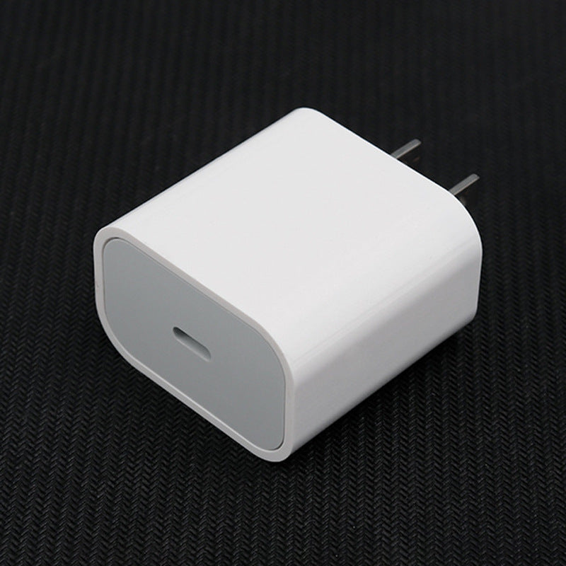 A white USB-C fast charging wall adapter with two flat pins, resting on a textured black surface.