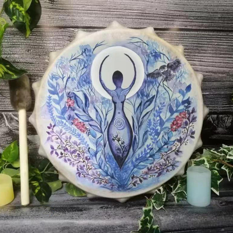 Decorative drum with artistic design of a woman and nature elements on a wooden surface.