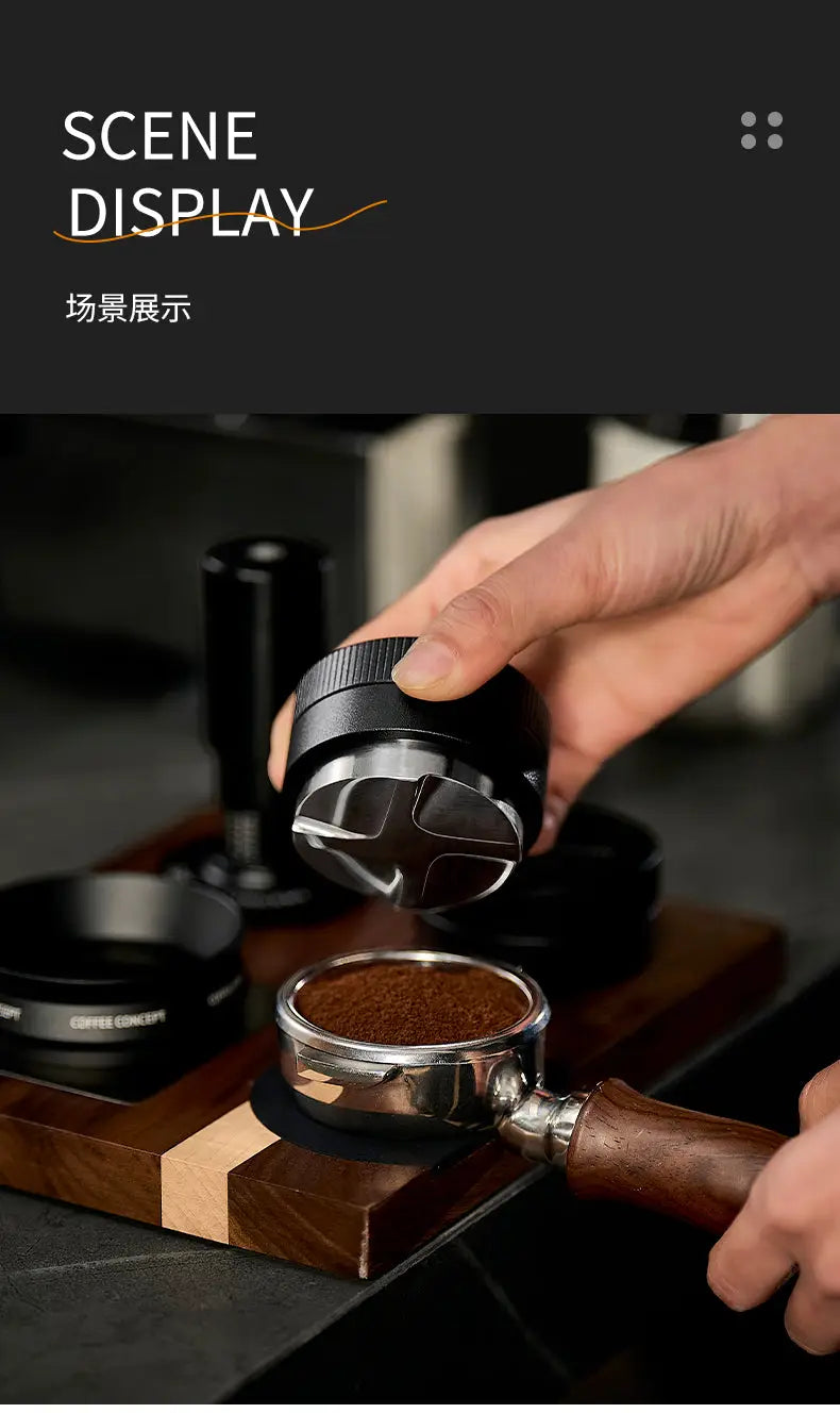 Hand using a stainless steel vertical striped gravity espresso distributor to evenly level fresh coffee grounds in a portafilter on a wooden barista station.