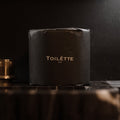 Black toiletry bag with 'TOILETTE NYC' branding on a dark background. 100% Premium Bamboo Toilètte Rolls: Tree-free, lab-tested and 100% free of PFAS, formaldehyde, and elemental chlorine.