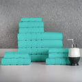 Stack of teal towels on a gray surface with a soap dispenser. 12-Piece: Bibb Home Egyptian Cotton Towel Set.