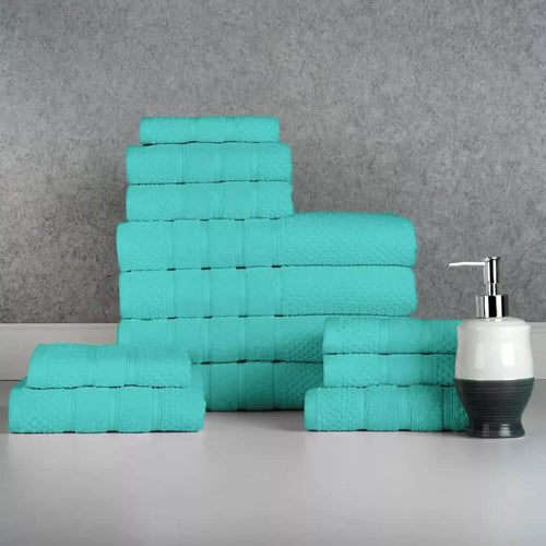 Stack of teal towels on a gray surface with a soap dispenser. 12-Piece: Bibb Home Egyptian Cotton Towel Set.