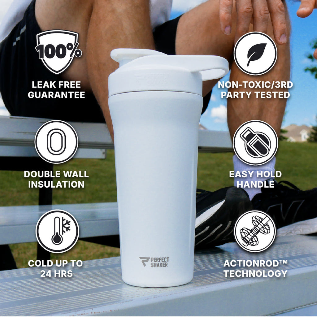 A white Perfect Shakes double-walled insulated shaker bottle with a flip-top lid, placed on a picnic table outdoors. The image includes several feature callout badges with text such as '100% Leak Free Guarantee,' 'Double Wall Insulation,' 'Cold Up to 24 Hrs,' 'Non-Toxic/3rd Party Tested,' 'Easy Hold Handle,' and 'Actionrod Technology.