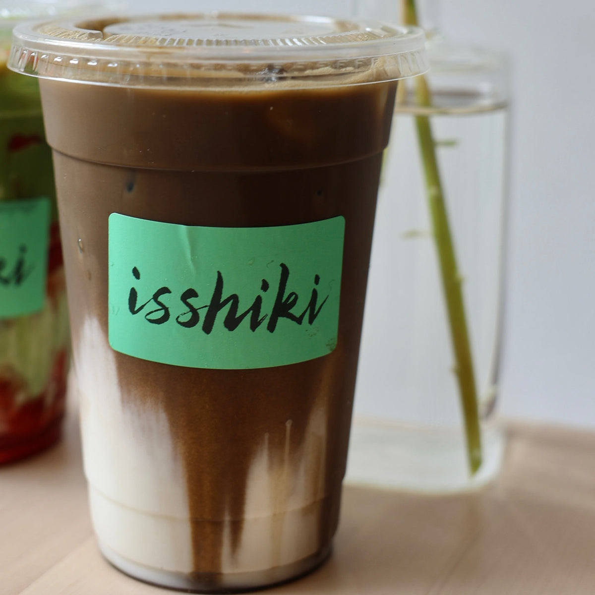Mocha iced coffee in a cup with 'isshiki' label on a wooden surface.