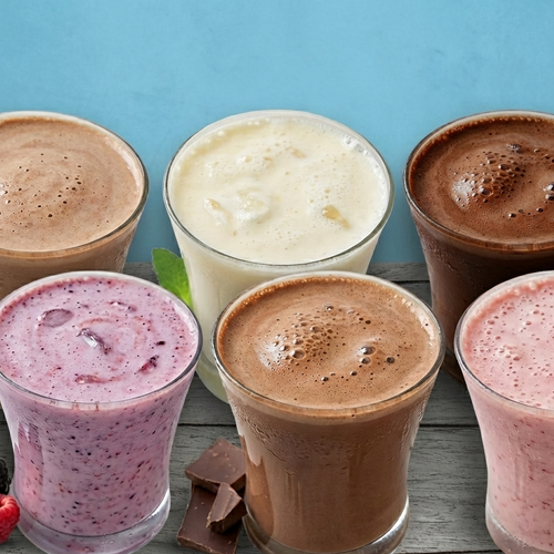 Assorted smoothies in clear glasses on a wooden surface with a blue background
