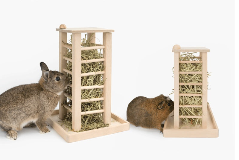 Two small animals interacting with hay towers on a white background. ooden rabbit stand. Pet stand.