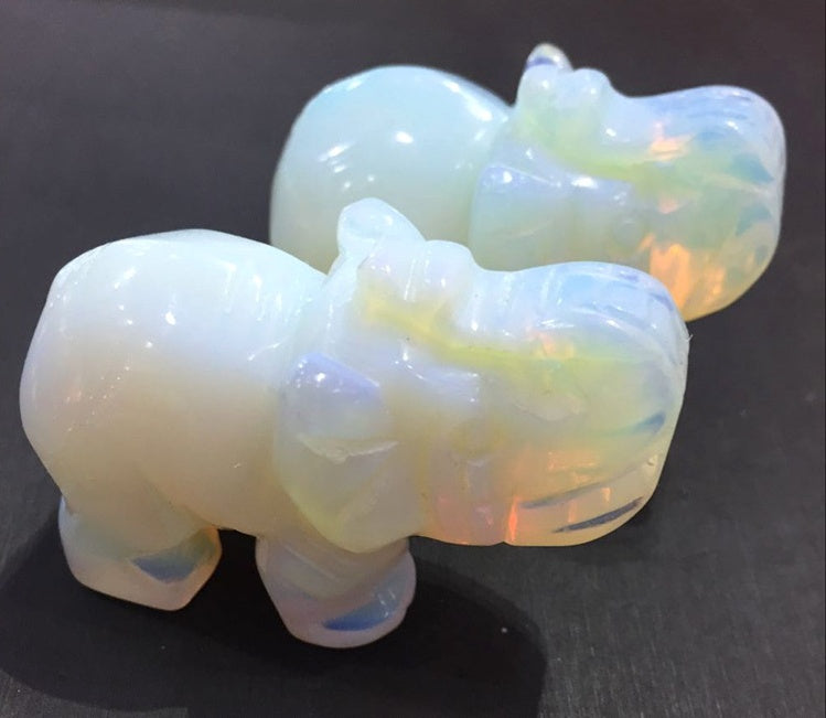 Two opalite elephant carvings on a dark surface