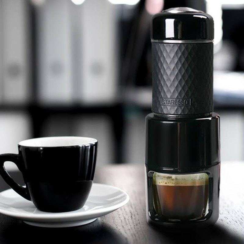 Portable manual espresso coffee maker with compact black design, reusable coffee cup and pressure brewing system for rich espresso at home, office or travel.