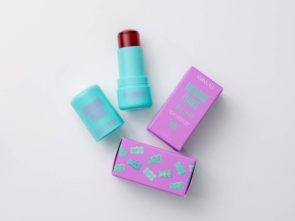 Mermaid Pearls LOLLIPOP Berry Lip & Cheek Tint with aqua twist-up tube and purple gummy bear packaging, hydrating jelly formula for buildable rosy color on lips and cheeks, vegan, cruelty-free clean beauty makeup.