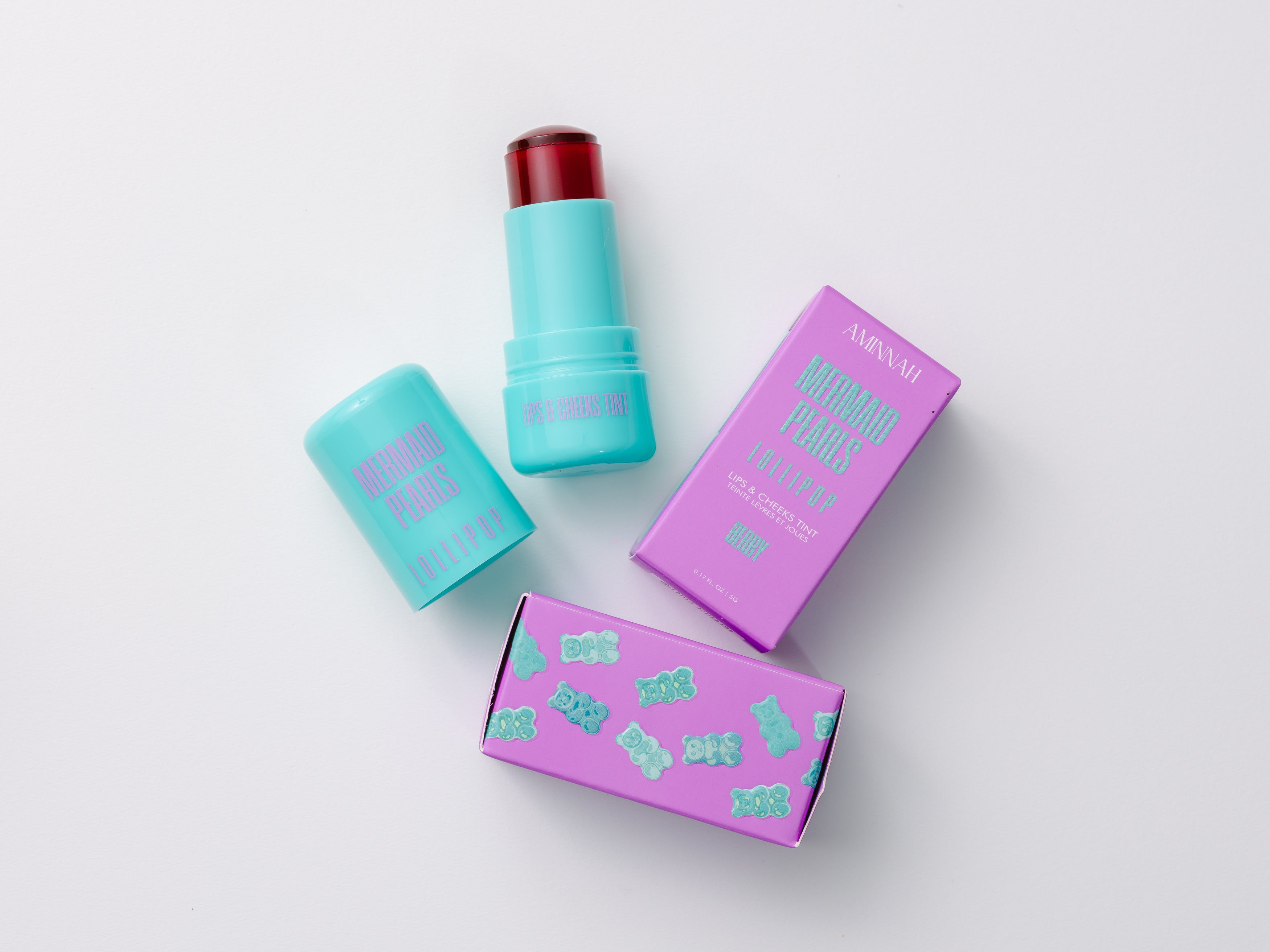 Mermaid Pearls LOLLIPOP Berry Lip & Cheek Tint with aqua twist-up tube and purple gummy bear packaging, hydrating jelly formula for buildable rosy color on lips and cheeks, vegan, cruelty-free clean beauty makeup.
