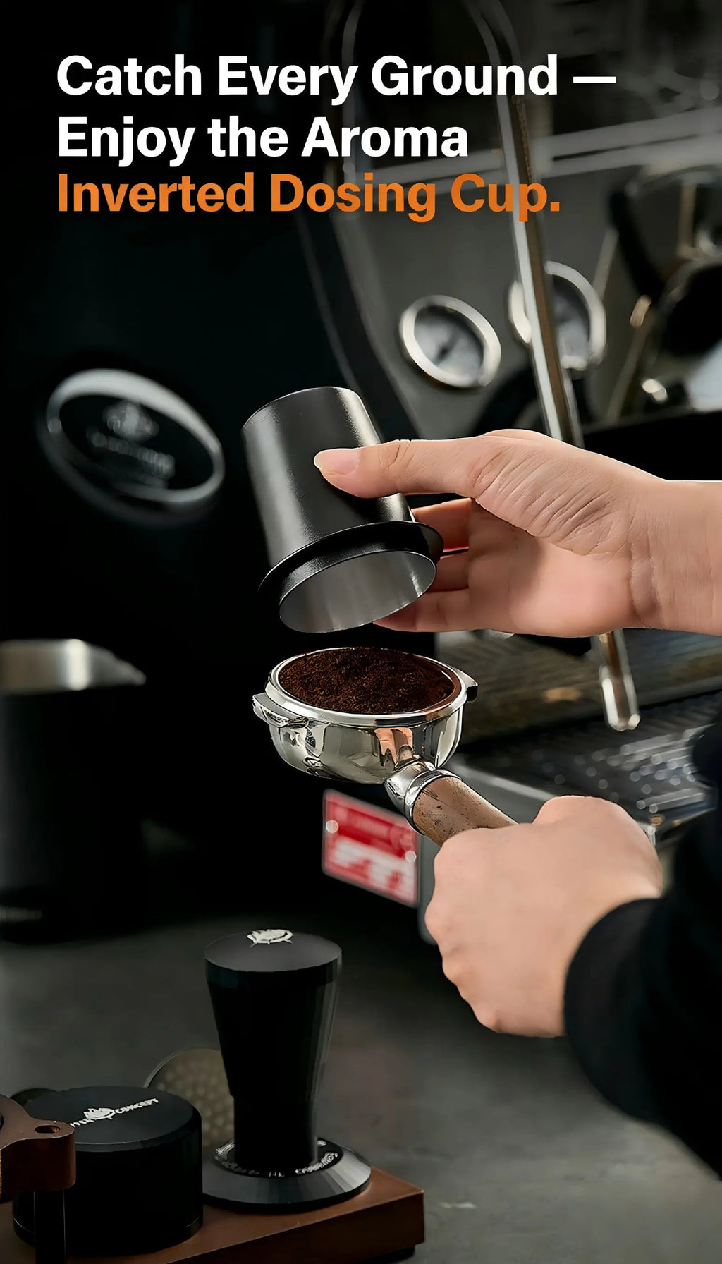 Person using a black inverted espresso dosing cup to transfer freshly ground coffee into a portafilter beside a professional espresso machine and coffee grinder.