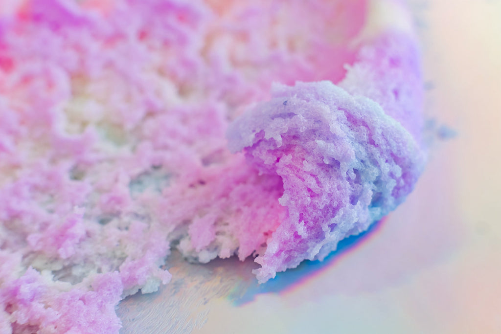 "Unicorn Dreams" Sugar Scrub close-up showcasing fluffy pastel whipped texture made with natural ingredients for gentle exfoliation and deep hydration. Clean beauty, cruelty-free, vegan skincare from a female-owned brand featuring sugar, shea butter, mango butter, cocoa butter, coconut oil, jojoba oil, aloe vera, vitamin E, and shimmering cosmetic mica for soft, radiant skin.