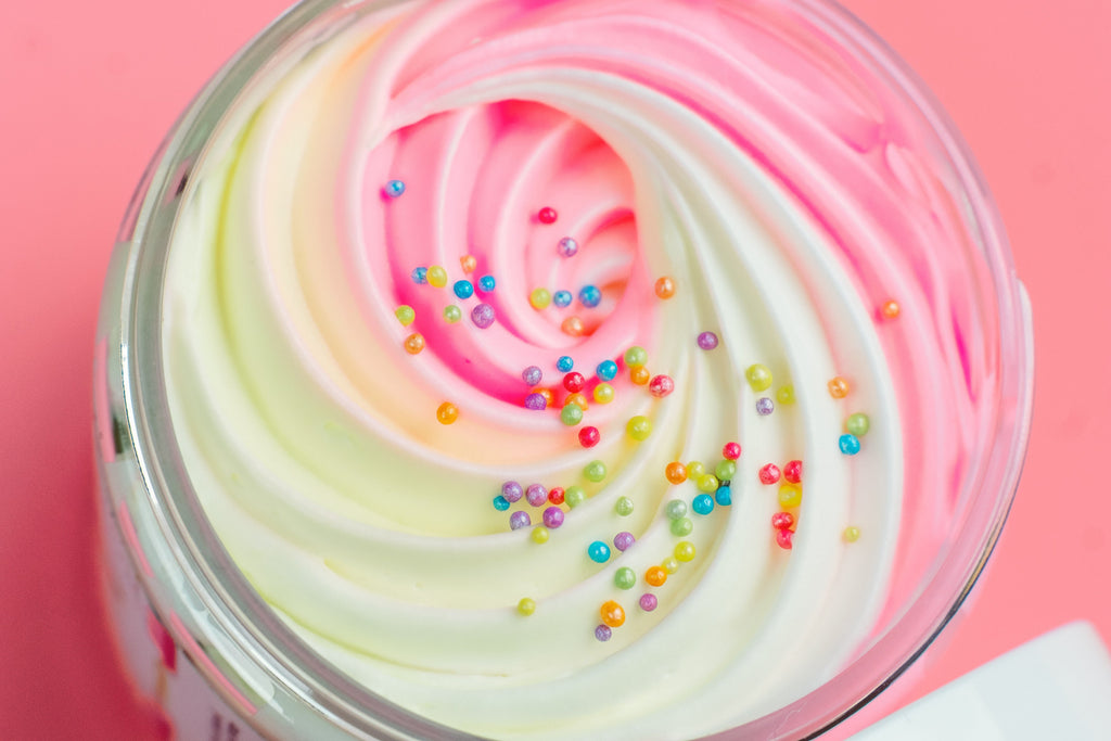 Close-up of AMINNAH Birthday Cake Whipped Body Butter featuring a pink, white, and pastel whipped texture topped with colorful sprinkles. Moisturizing body butter made with natural ingredients including organic shea butter, cocoa butter, mango butter, coconut oil, jojoba oil, and vitamin E. Clean Beauty, cruelty-free, vegan, female-owned brand skincare proudly made in the USA, available at Tree of Life Grocers.