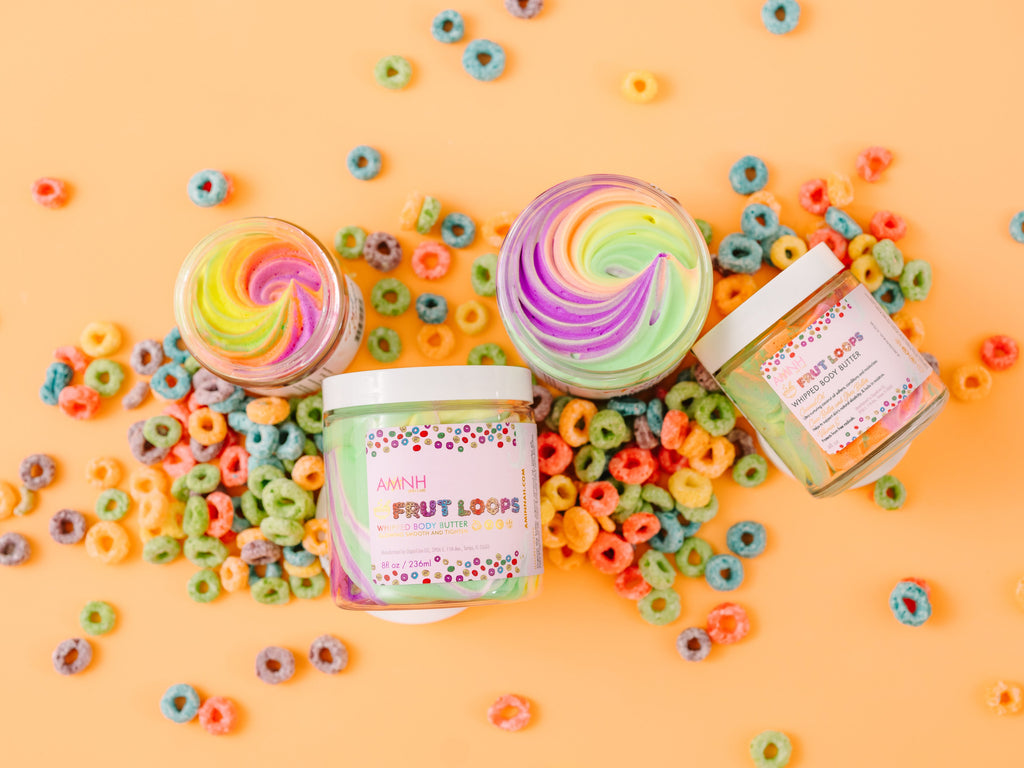 AMINNAH Frut Loops Whipped Body Butter with colorful rainbow swirls displayed alongside cereal-inspired accents. This clean beauty, cruelty-free, vegan body butter is made with natural ingredients including shea butter to deeply moisturize, nourish, and soften skin. Female-owned brand offering hydrating skincare for all skin types, available at Tree of Life Grocers.