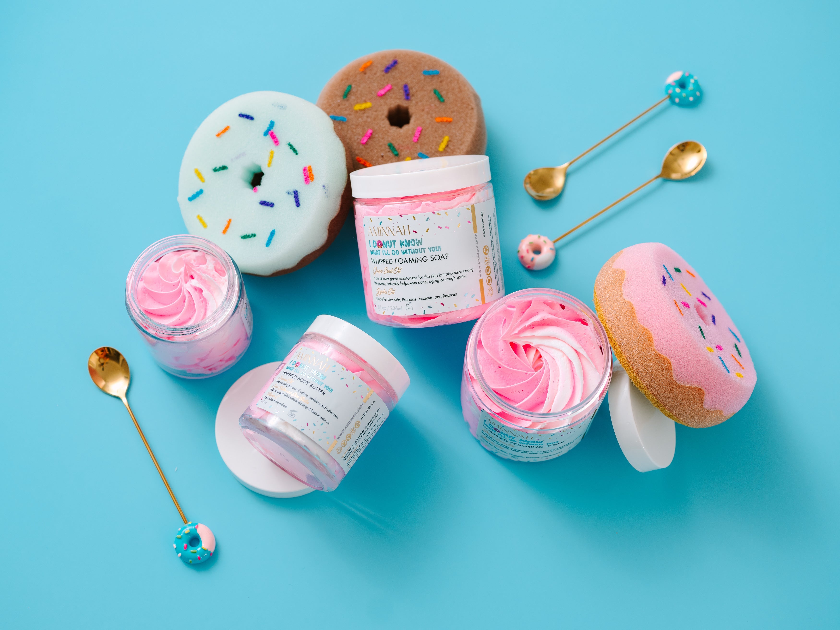 I Donut Know What I'll Do Without You! Whipped Body Butter in a playful donut-inspired display featuring fluffy pink whipped body butter in open jars, decorative sprinkle donuts, and gold spoons. Richly formulated with shea butter, cocoa butter, mango butter, coconut oil, jojoba oil, vitamin E, and fruit extracts to deeply moisturize, soften, and nourish dry skin. Cruelty-free, made with clean ingredients, and perfect for daily hydration.