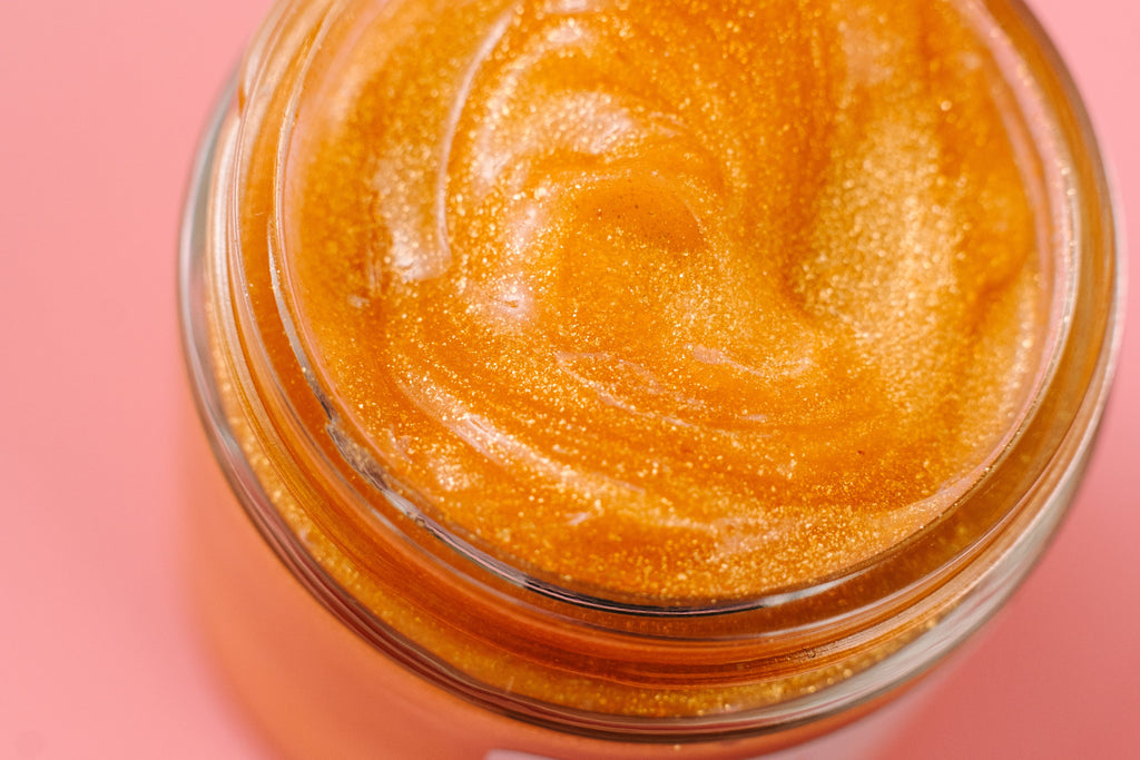 24K Golden Jelly Face Mask in a glass jar with luxurious shimmering gold gel texture. Clean beauty, cruelty-free, vegan skincare made with natural ingredients including aloe vera, rose extract, vitamin E, coconut oil, 24K gold flakes, and jojoba beads. Female-owned brand formulated to deeply hydrate, soothe, tone, reduce inflammation, support anti-aging, improve skin elasticity, soften the appearance of fine lines, and promote a radiant, youthful, glowing complexion.