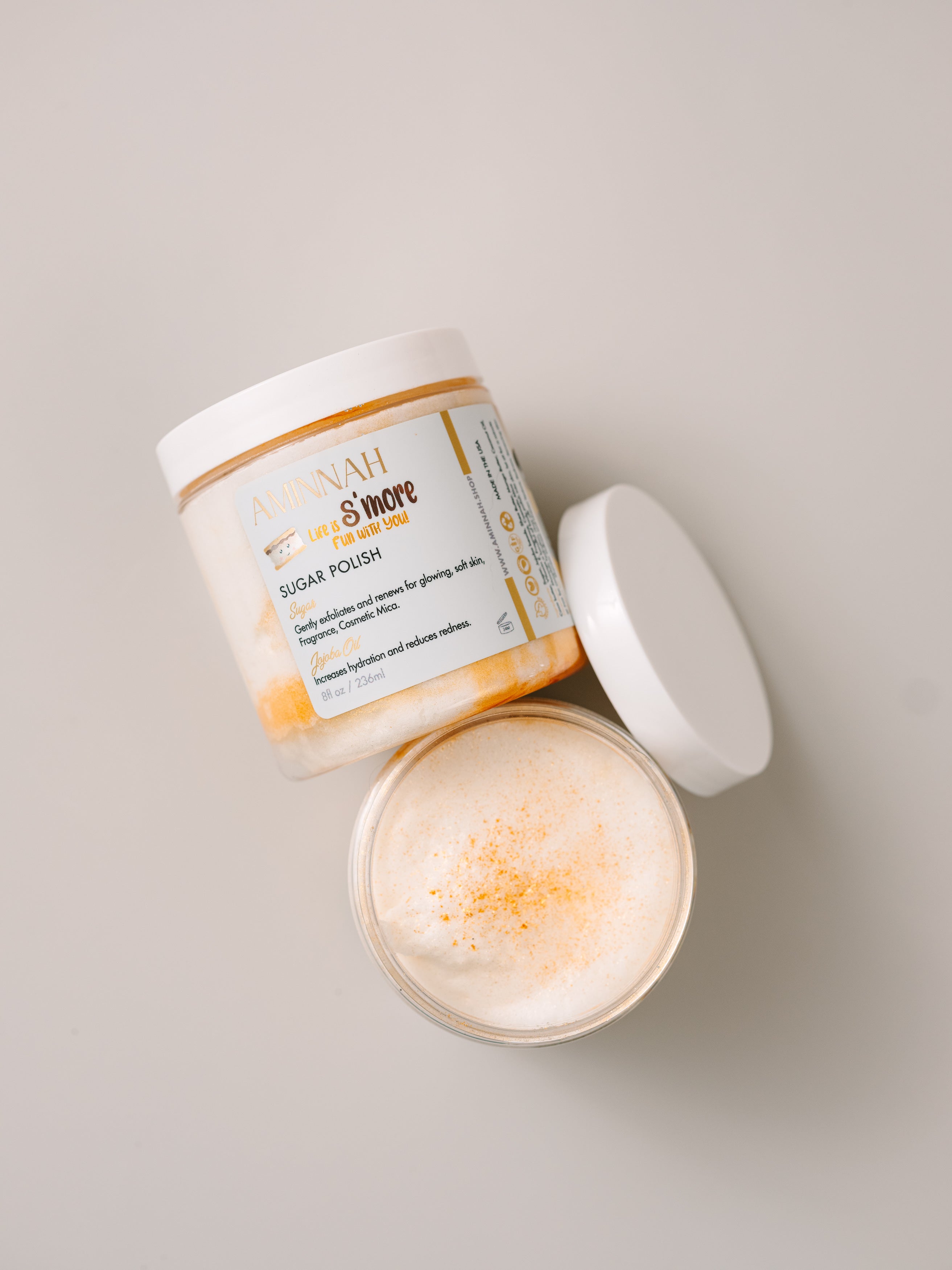 AMINNAH® Life Is S’more Fun With You™ Sugar Scrub with 24K Gold Dust in open jar, moisturizing sugar polish made with shea butter, mango butter, cocoa butter, coconut oil, jojoba oil, aloe vera, and vitamin E for clean beauty, vegan, cruelty-free skincare.
