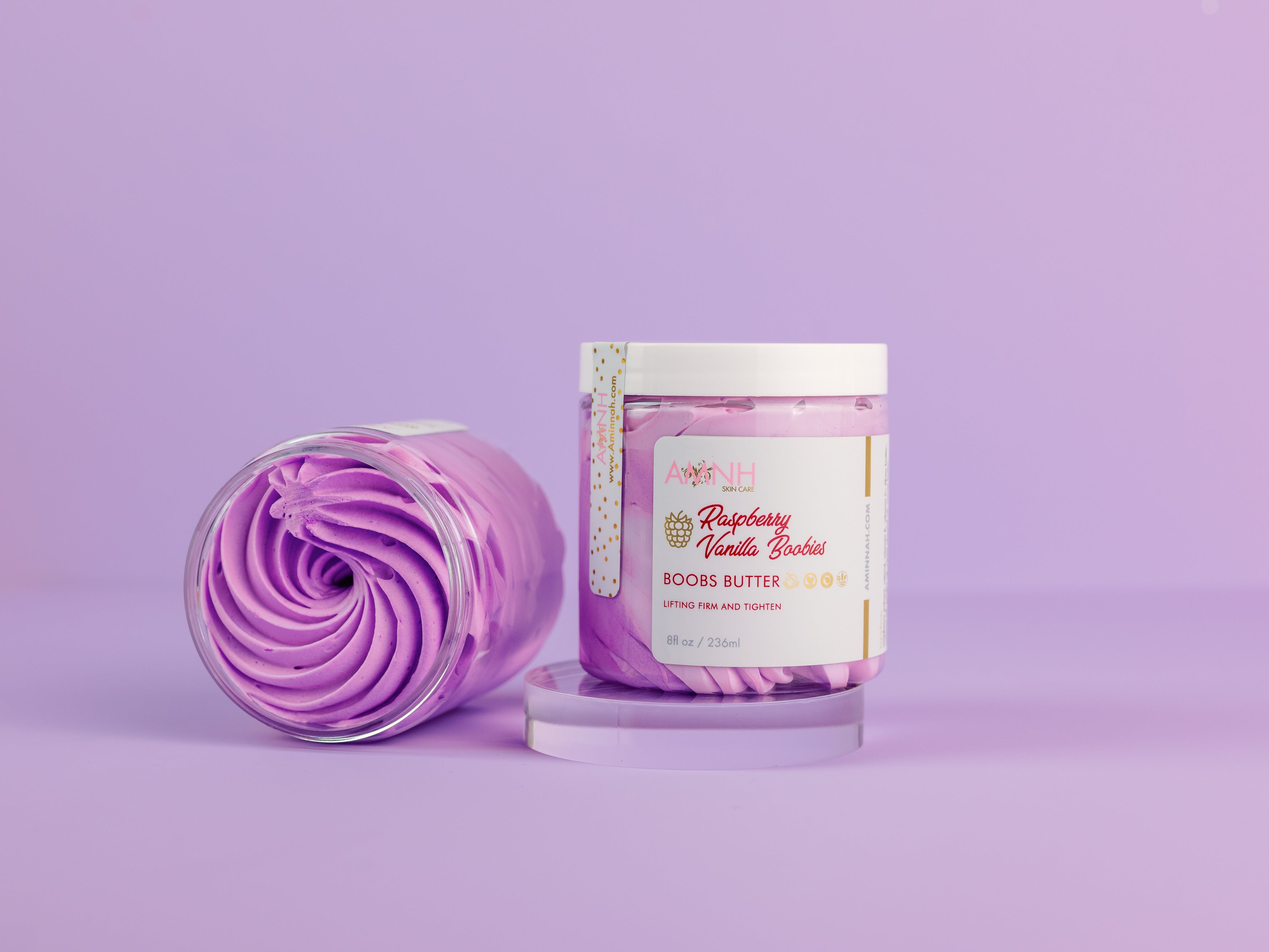 Raspberry Vanilla Boob Butter in decorative jar with whipped purple body butter beside it, moisturizing body butter for smooth, nourished skin by Aminnah Skincare. Clean beauty, cruelty-free, vegan, made with naturally derived ingredients, and crafted by a female-owned brand. Available at Tree of Life Grocers.