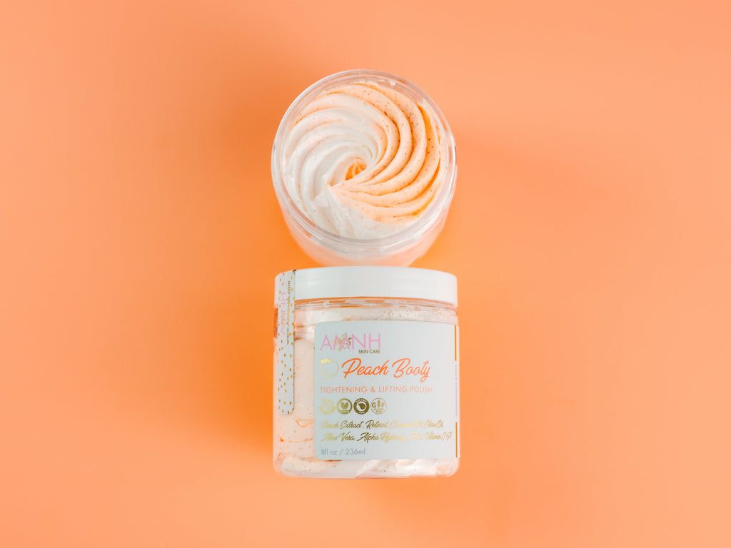 Jar of peach body scrub with a swirled design on an orange background. Open jar of AMINNAH Peach Booty Tightening & Lifting Scrub showcasing its whipped exfoliating texture with the product jar below on a peach background. Clean beauty, cruelty-free, vegan body scrub made with natural ingredients including Peach Extract, Aloe Vera, Retinol, and Apricot Seed Powder from a female-owned brand.