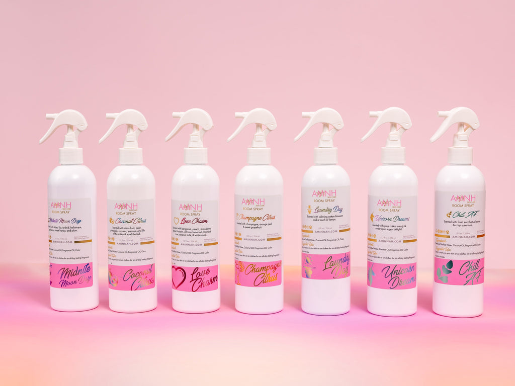 AMINNAH Room Spray collection featuring Midnite Moon Daze alongside six additional scented room sprays displayed on a soft pink gradient background. Clean beauty, cruelty-free, vegan home fragrance sprays crafted with naturally derived ingredients including steamed distilled water, coconut oil, and fragrance oil to refresh rooms, linens, and fabrics. Female-owned brand available at Tree of Life Grocers.