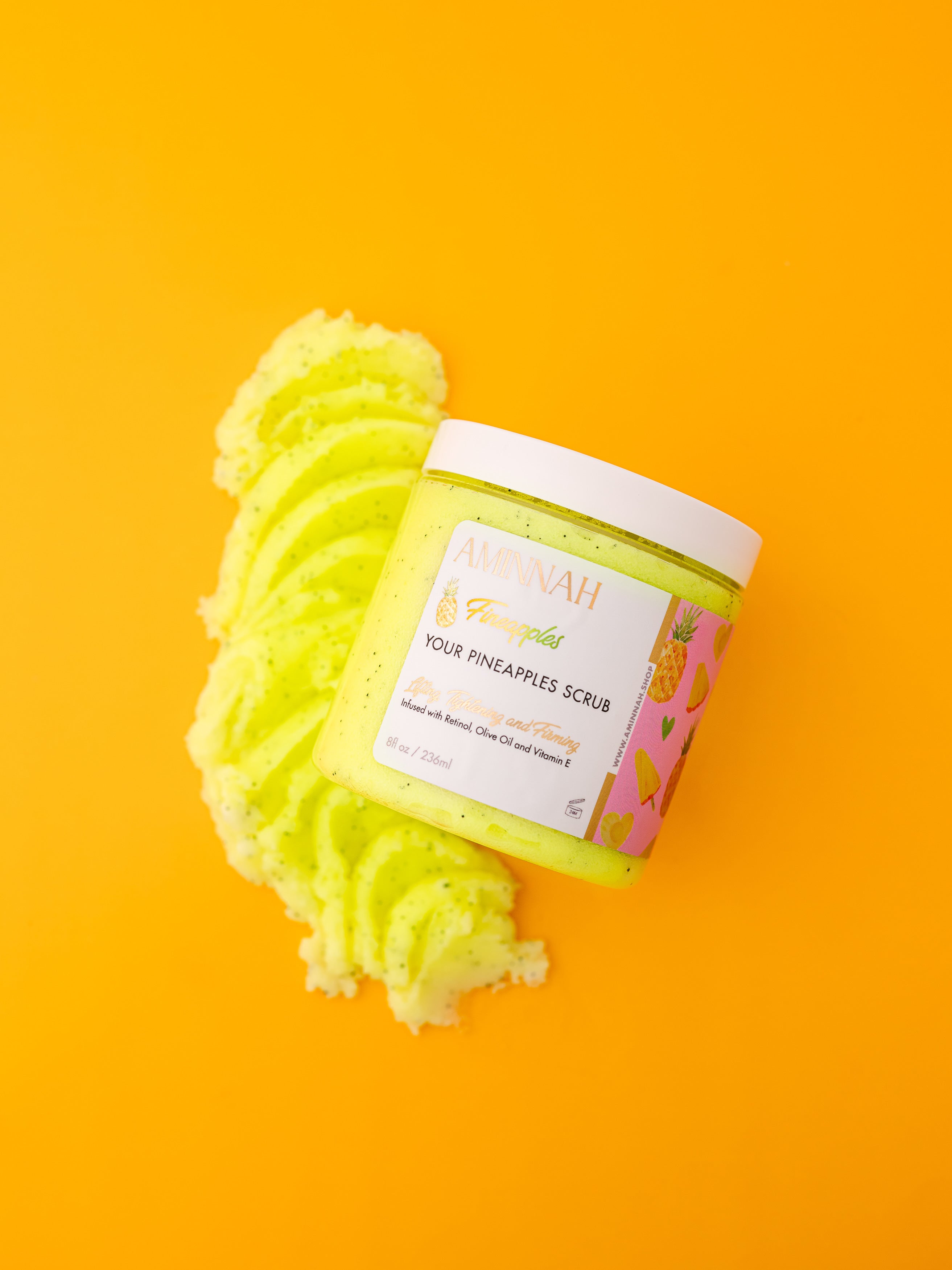AMINNAH Fineapples Boob Sugar Scrub with pineapple, retinol, and vitamin E in a luxury skincare jar on a vibrant yellow background. Anti-aging exfoliating body scrub made with natural ingredients to help smooth, soften, and renew skin. Clean beauty, vegan, cruelty-free, paraben-free, gluten-free formula from a female-owned brand with recyclable packaging for radiant, healthy-looking skin.