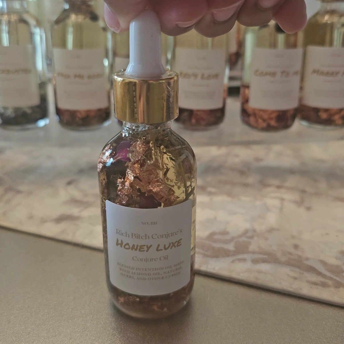 Bottle of 'Honey Luxe' cosmetic oil with dropper, labeled 'Rich Birch Conifer', on a marble surface.