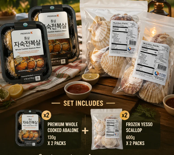 A seafood set displayed on a wooden table with two packaged abalone shells and several clear bags of scallops, plus two small bowls of sauce and lemon wedges. Text at the bottom reads 'SET INCLUDES' and lists premium whole cooked abalone (130g x 2 packs) and frozen yesso scallop (600g x 2 packs).