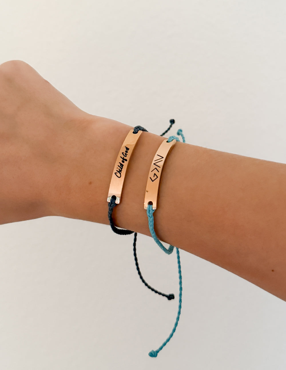 Two copper-toned Christian Religious Child of God beaded string bracelets worn on a wrist, set against a simple, clean background.