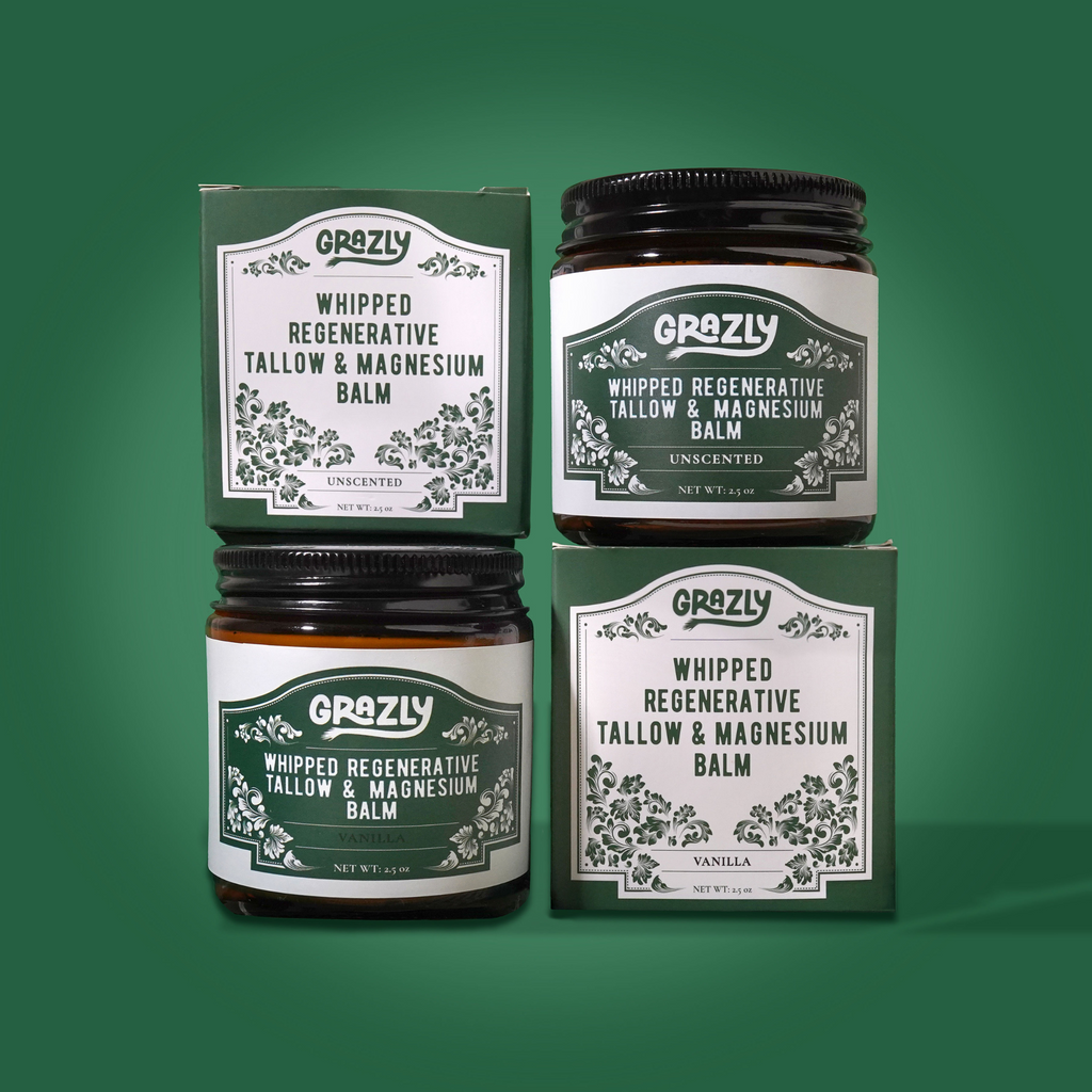 Grazly Whipped Regenerative Tallow & Magnesium Balm in amber glass jars with Unscented and Vanilla varieties displayed alongside green product boxes on a matching green background.