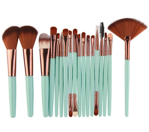 Set of makeup brushes with green handles and burnt orange brown bristles on a white background