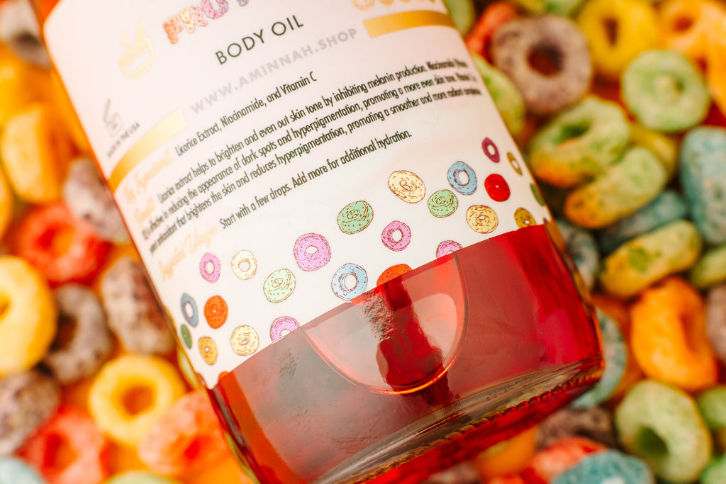 Frut Loops Body Oil bottle with colorful fruity cereal background by a female-owned brand. Clean beauty, cruelty-free, vegan body oil made with natural ingredients including niacinamide, licorice extract, and vitamin C to nourish, hydrate, brighten, and promote radiant glowing skin with a sweet fruity cereal-inspired scent.