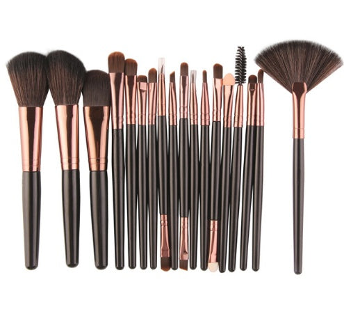 Set of makeup brushes with black and rose gold handles on a white background