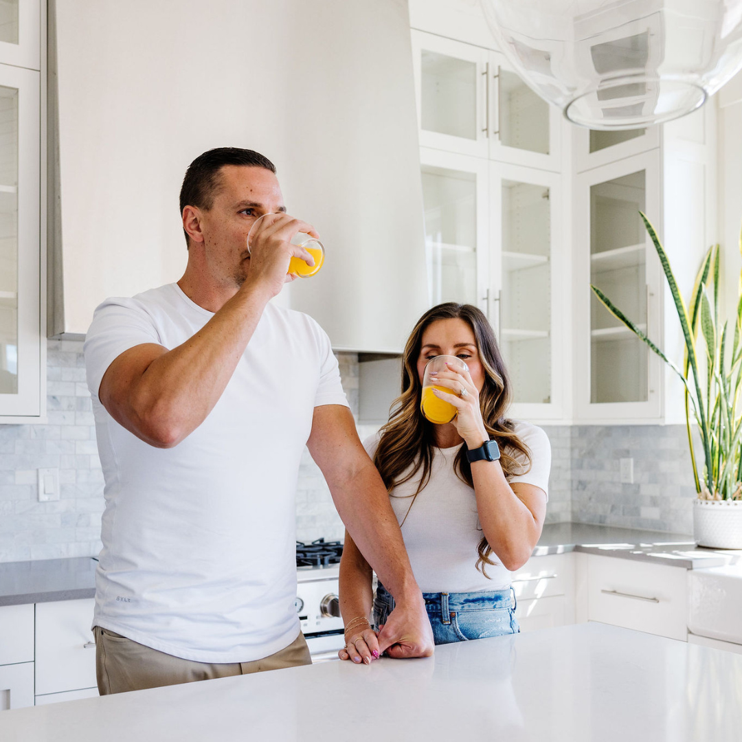 Man and woman drinking orange juice in a modern kitchen