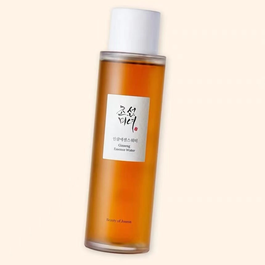 Beauty of Joseon Ginseng Essence Water skincare bottle with amber liquid, white cap, and Korean label on a light beige background.