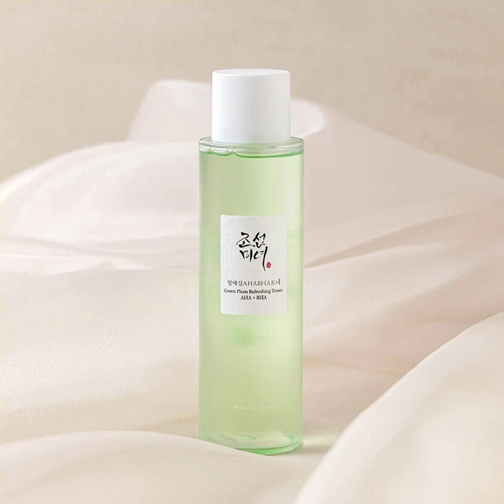 aBeauty of Joseon Green Plum Refreshing Toner bottle with light green toner, white cap, and Korean label on a soft cream fabric background.