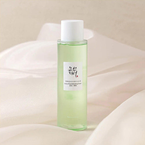 aBeauty of Joseon Green Plum Refreshing Toner bottle with light green toner, white cap, and Korean label on a soft cream fabric background.