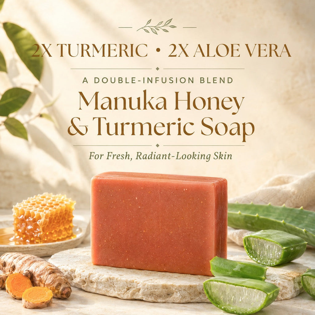 A rectangular bar of Manuka Honey & Turmeric Soap in a warm reddish-brown tone, displayed on a stone slab with aubergine, aloe vera slices, turmeric root, and honeycomb. The background is a soft beige with elegant text detailing the ingredients: 2x Turmeric and 2x Aloe Vera.