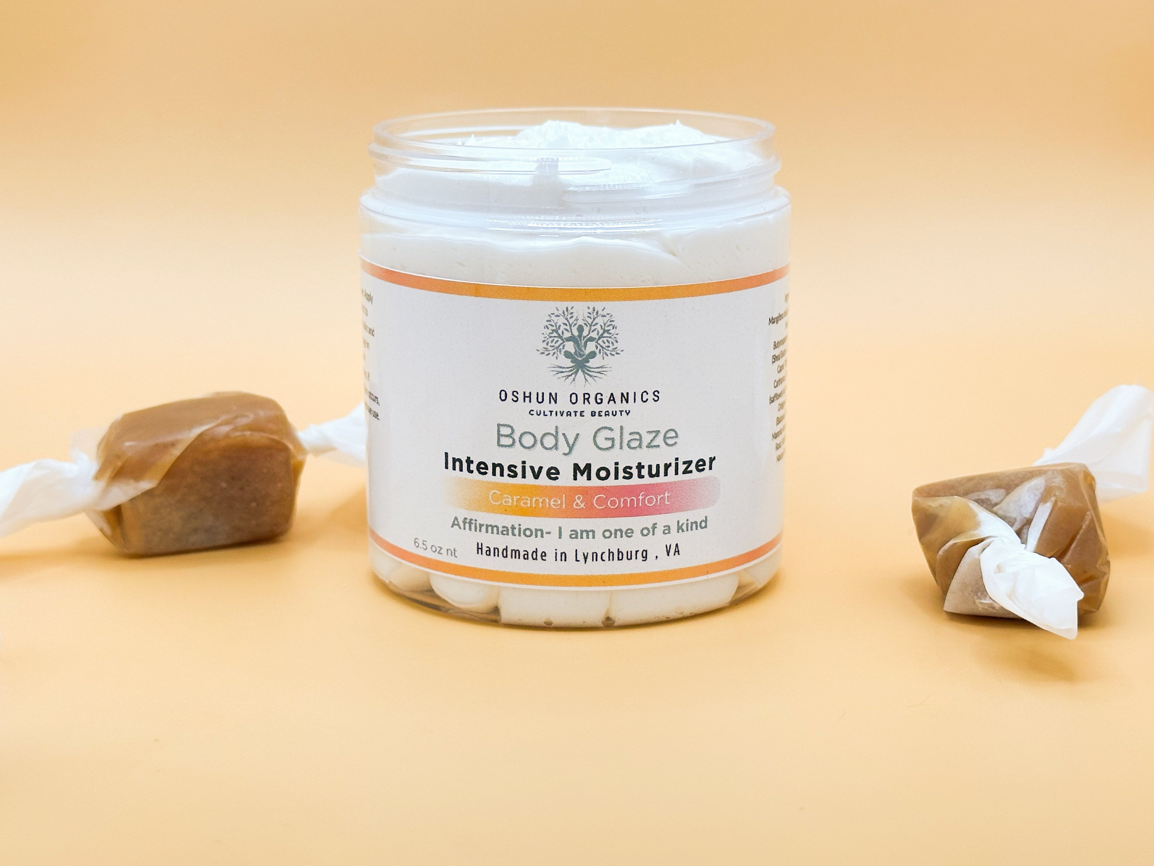 Oshun Organics Body Glaze Intensive Moisturizer Caramel & Comfort whipped plant-based body butter in a 6.5 oz jar with caramel candies on a warm beige background