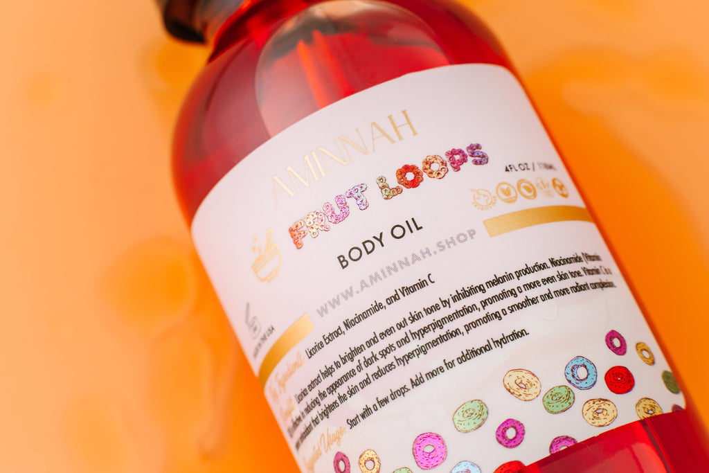 Frut Loops Body Oil bottle with a vibrant fruity cereal-inspired design on a warm yellow background. Clean beauty, cruelty-free, vegan body oil made with natural ingredients including niacinamide, licorice extract, and vitamin C to deeply nourish, hydrate, brighten, and promote radiant glowing skin. Premium skincare from a female-owned brand.