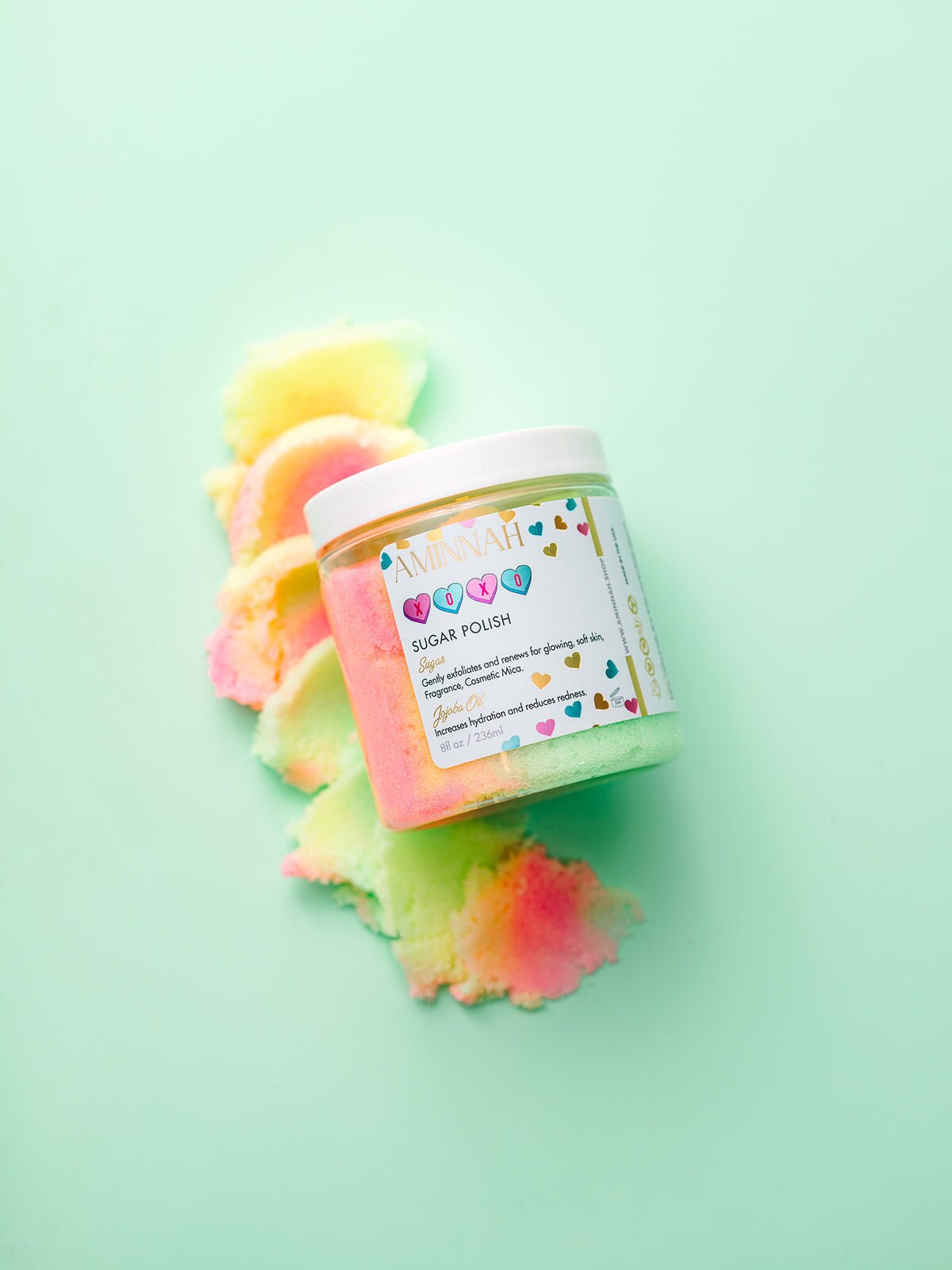 XOXO Sugar Scrub by Aminnah displayed in colorful pastel sugar polish, vegan clean beauty body scrub made with natural ingredients, cruelty-free skincare, female-owned brand, moisturizing exfoliating scrub for soft, smooth, glowing skin