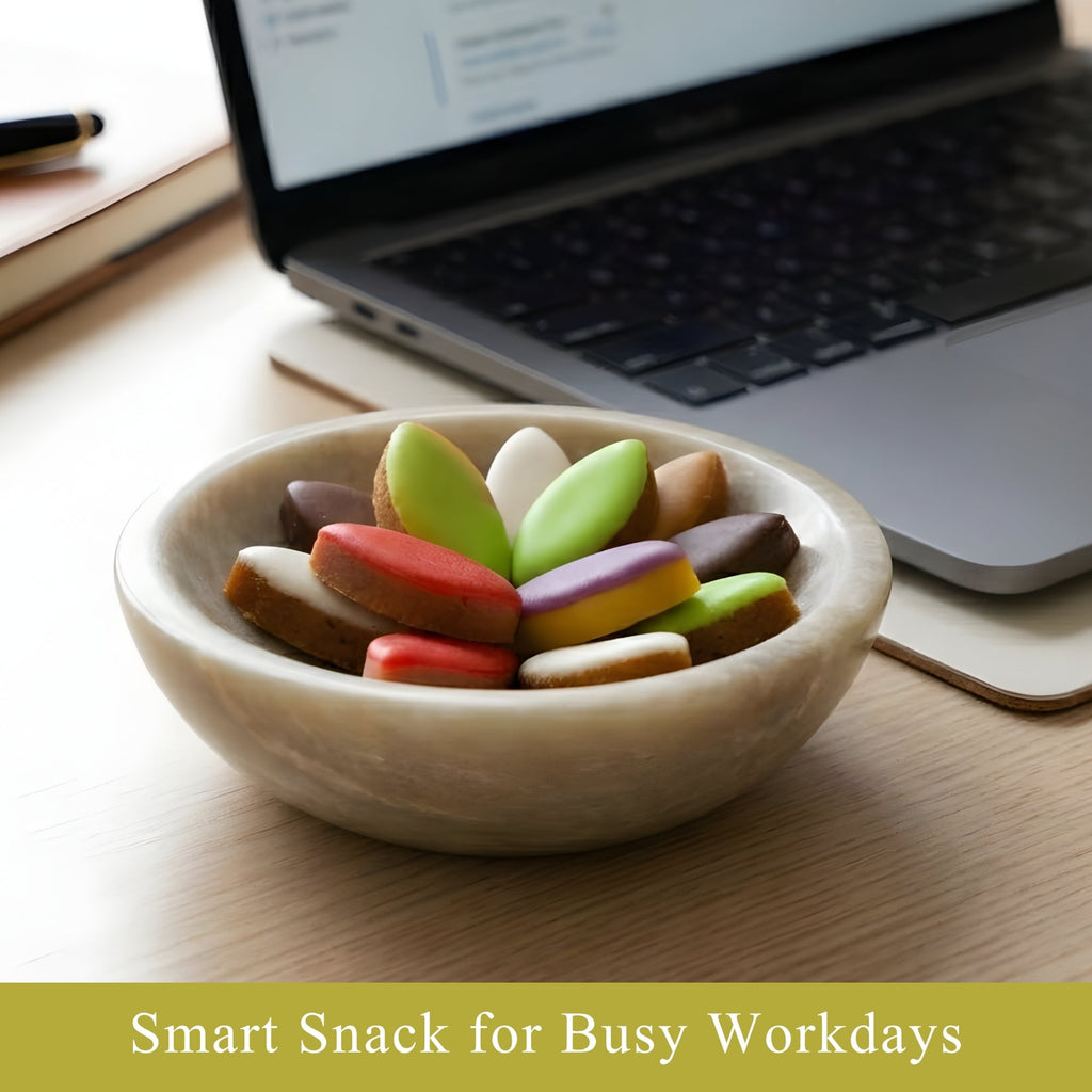 Bowl of colorful cookies on a desk with a laptop in the background