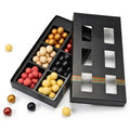Black chocolate box with compartments filled with assorted chocolates on a white background