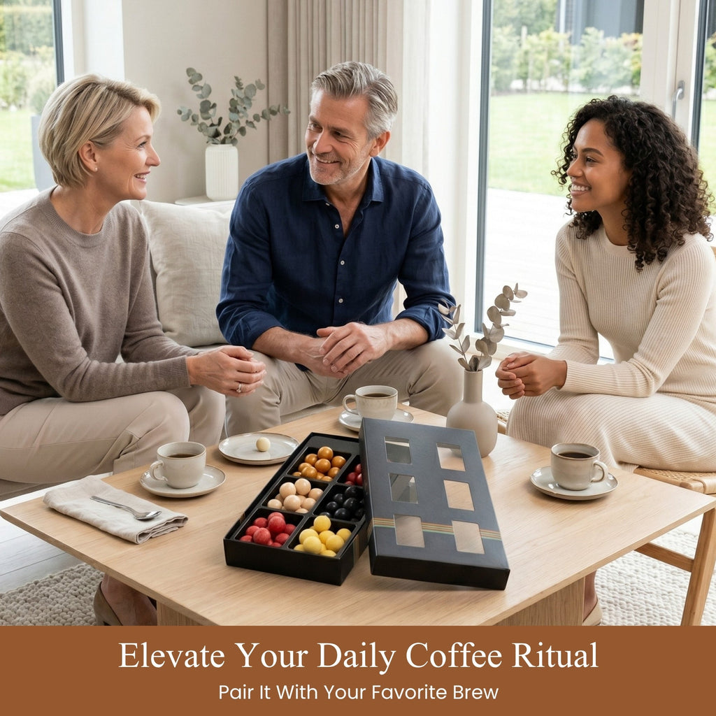 Three people sitting around a coffee table with a box of chocolates and coffee cups.