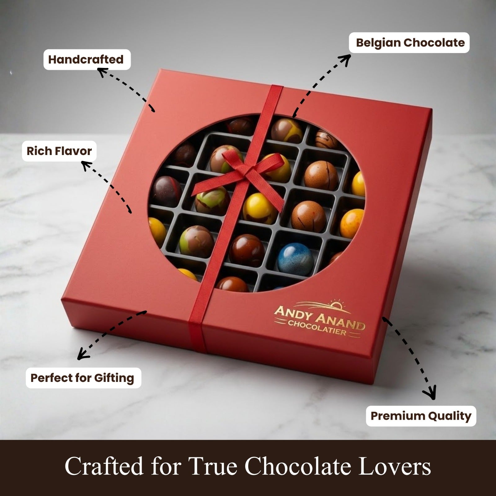 Red chocolate box with a bow, filled with assorted chocolates, on a marble surface. The box is branded 'Andy Anand Chocolatier'.