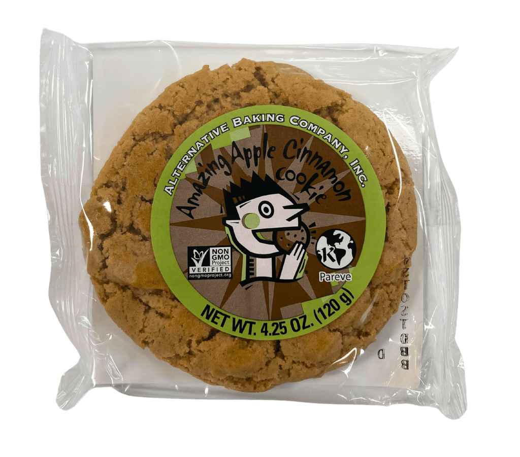 Apple Cinnamon vegan cookie in individual clear wrapper with branded label, white backing tray, and transparent background.