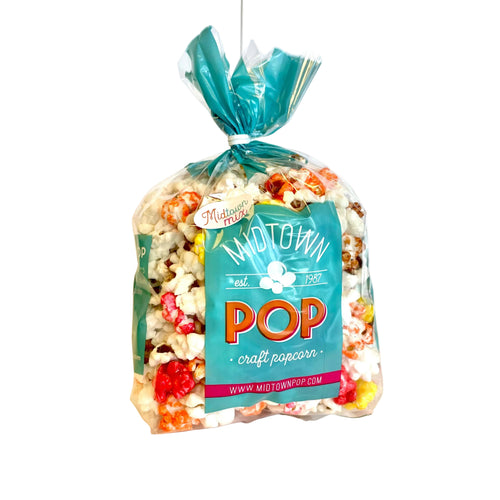 Colorful bag of Midtown Pop "Autumn" craft popcorn on a light background with festive caramel, cheddar, and white popcorn visible through clear packaging.