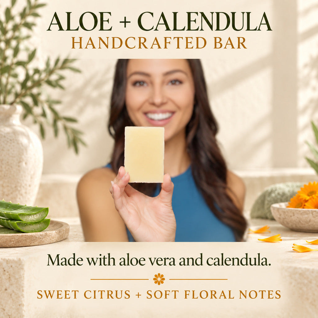 A woman holds up a rectangular bar of pale yellow soap in a warm, styled setting. Large text at the top reads 'ALOE + CALENDULA HANDCRAFTED BAR,' and text at the bottom says 'Made with aloe vera and calendula.