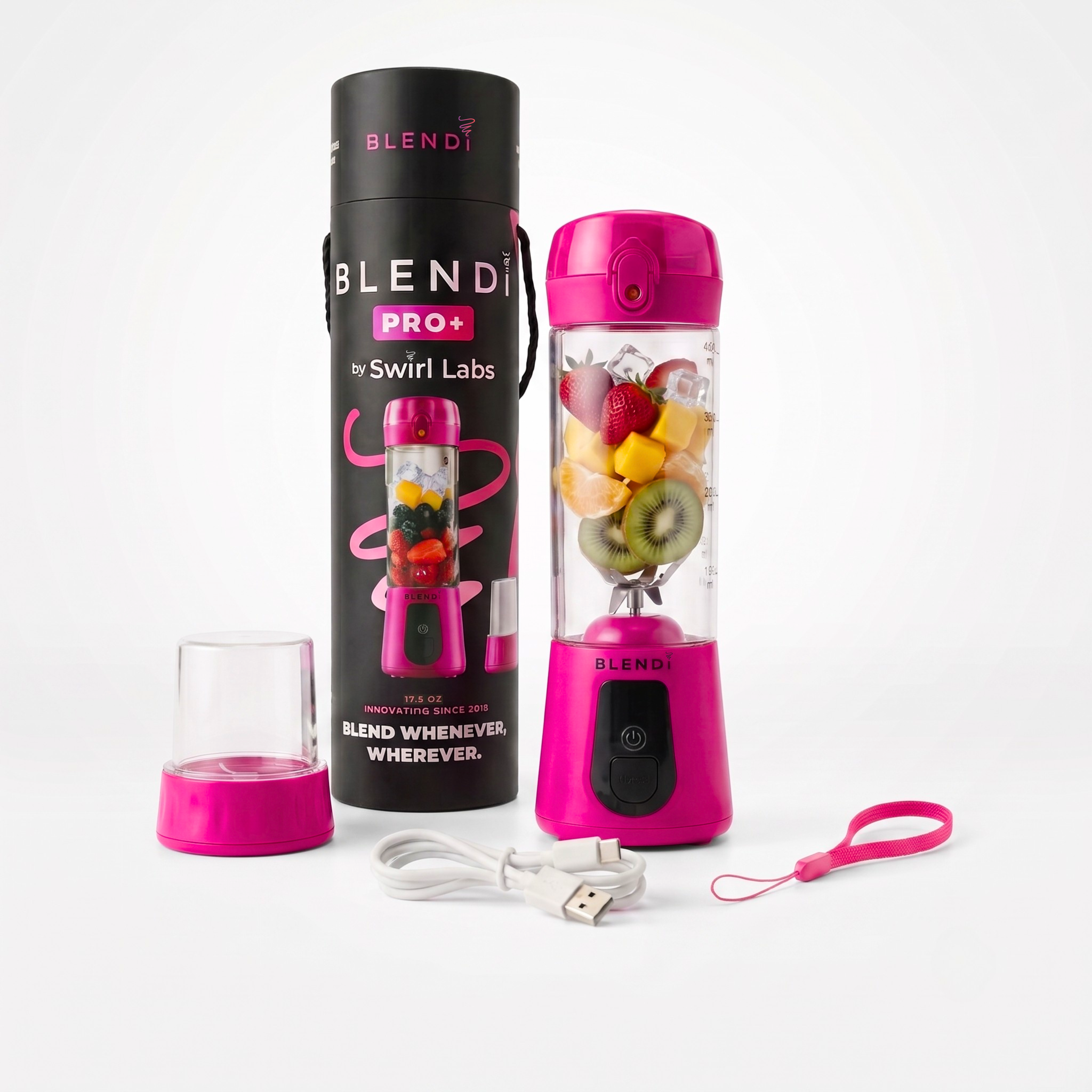 A pink portable blender bottle with its black cylindrical carrying case, a small clear travel cup, a USB charging cable, and a pink wrist strap, all arranged on a clean white background. The blender bottle is filled with fruit and is branded BLENDI.
