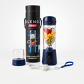 A portable electric blender set shown on a clean white background, including the blender bottle filled with fruit, its tall black carrying case, a small clear cup, a USB charging cable, and a blue wrist strap. The blender and case both show the Blendi brand name.