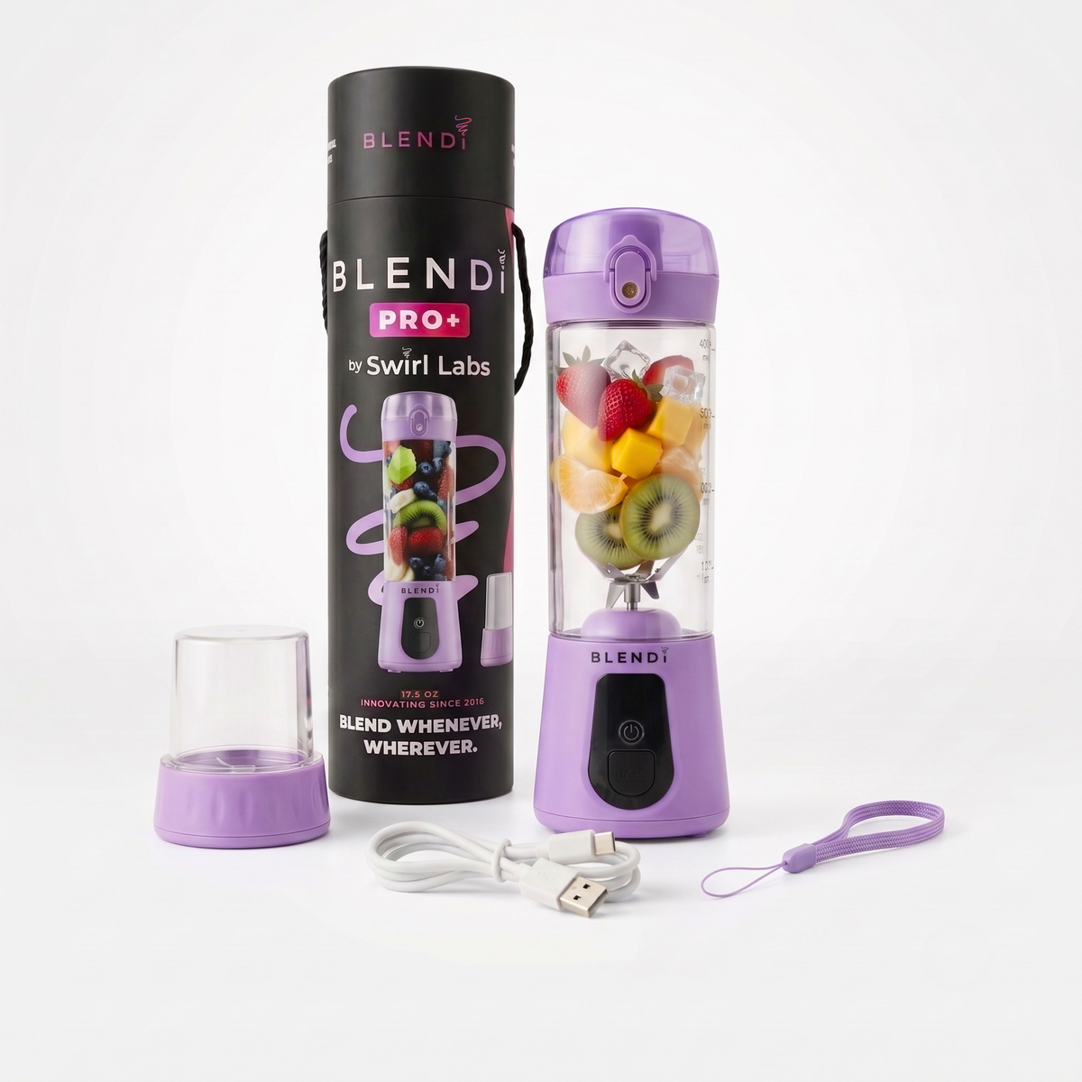 A purple Blendi Pro+ portable blender with a clear cup filled with fruit, shown next to its black cylindrical packaging, a small clear cup, a USB charging cable, and a purple wrist strap on a white background.
